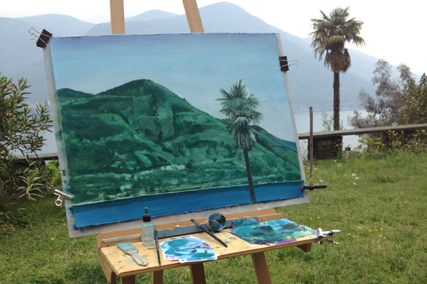 Home painting a landscape outside in ticino.